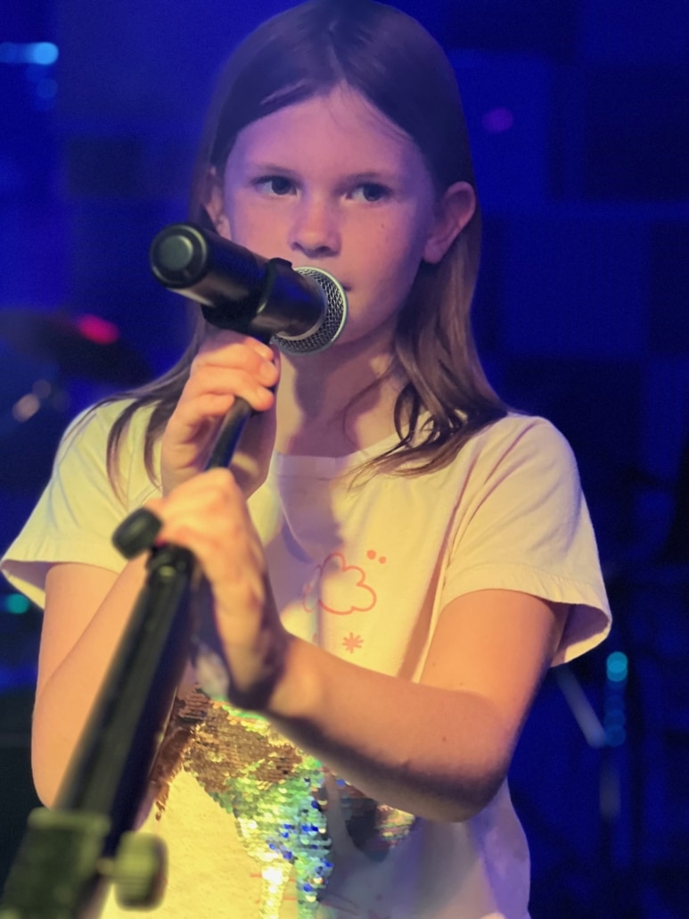 Spotlight of a voice lesson with a student on a microphone singing