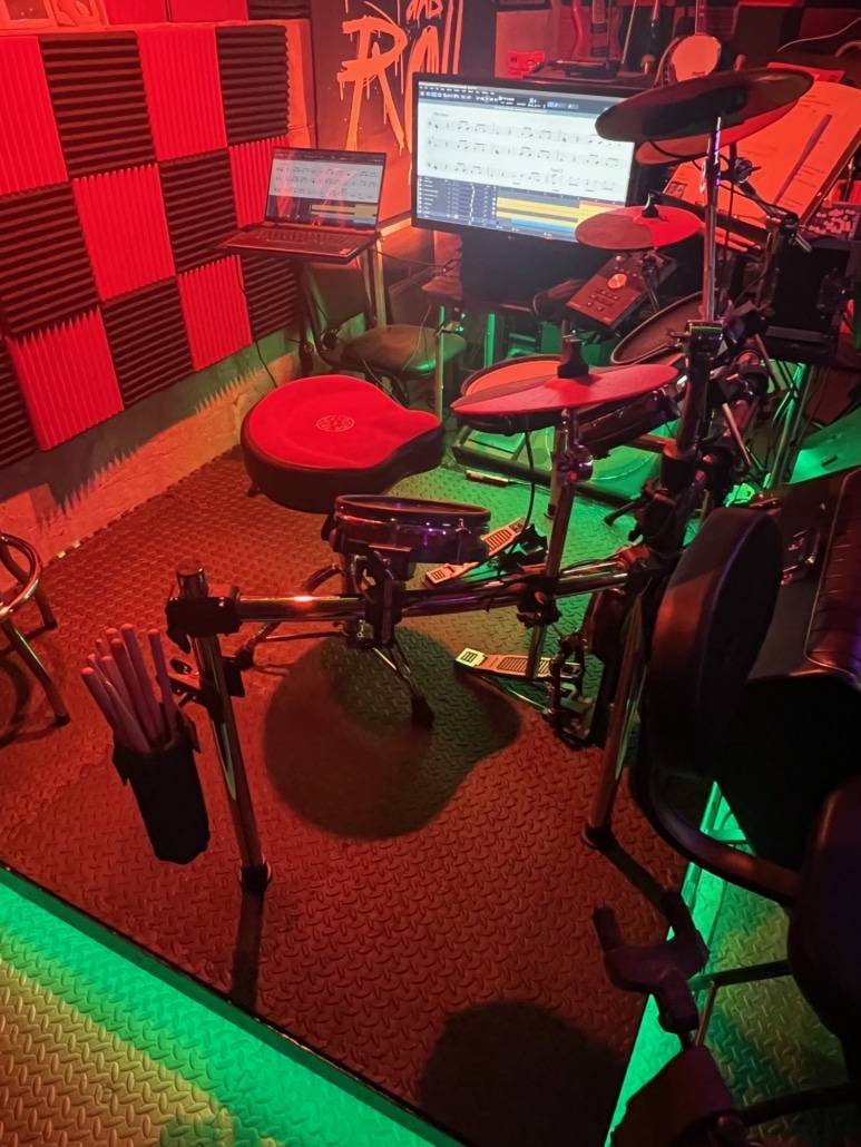 6 inch Drum riser with green lighting around the base props up an Alesis electronic drum kit